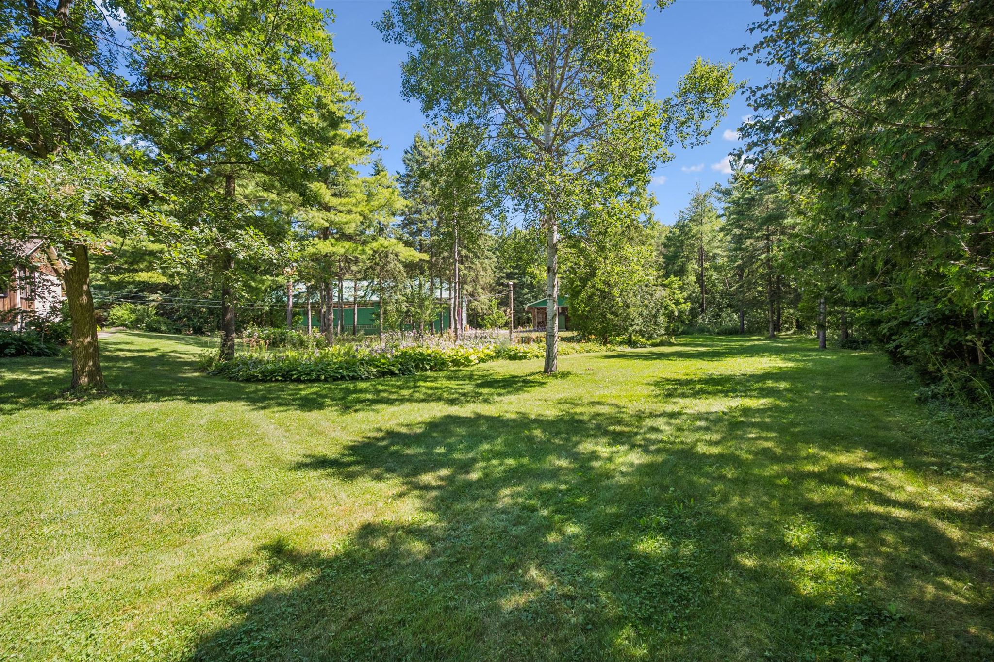 Lawn and mature trees toward the outbuildings